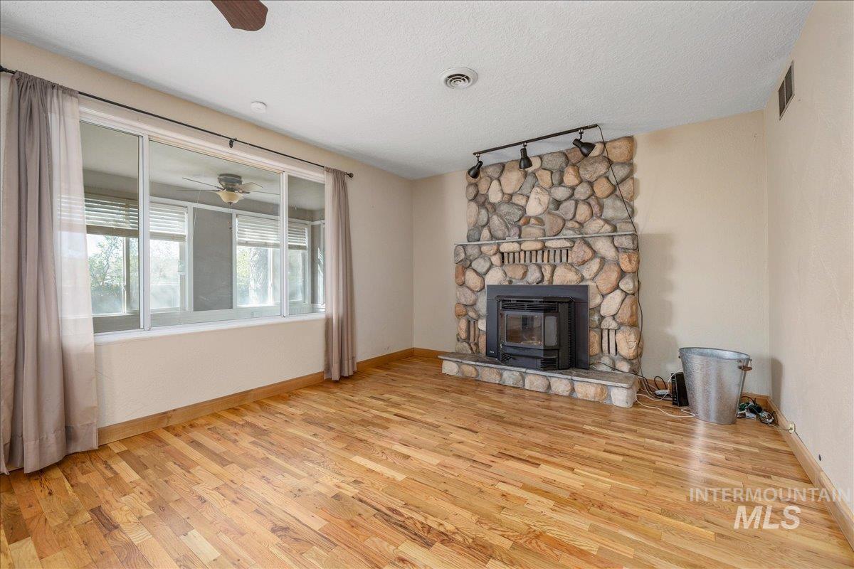 3002 Frozen Dog Road Emmett, ID 83617 - Photo 13 of 50 Unfurnished living room with a ceiling fan, track lighting, light wood finished floors, a textured ceiling, and a fireplace