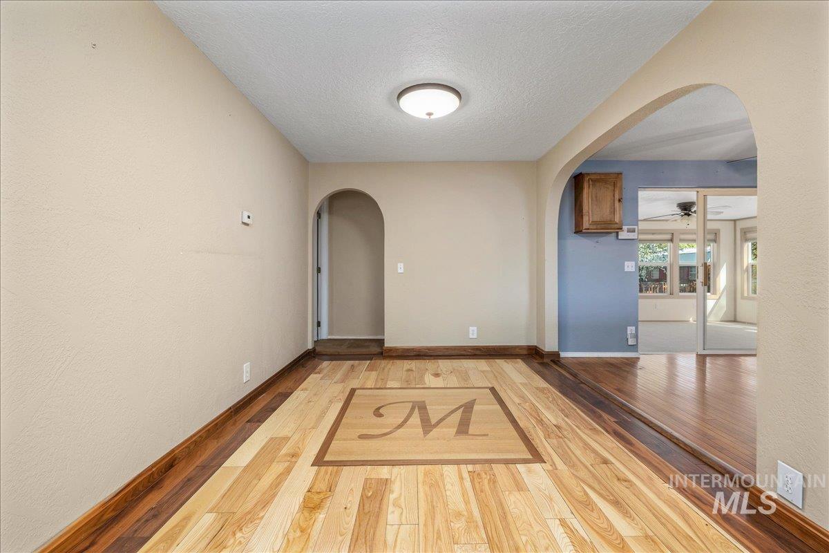 3002 Frozen Dog Road Emmett, ID 83617 - Photo 15 of 50 Hall with arched walkways, light wood-style floors, a textured ceiling, and a textured wall
