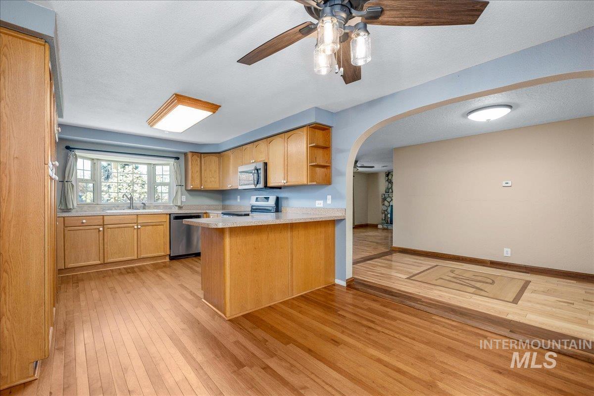 3002 Frozen Dog Road Emmett, ID 83617 - Photo 16 of 50 Kitchen with a peninsula, arched walkways, ceiling fan, light countertops, and light wood-style flooring
