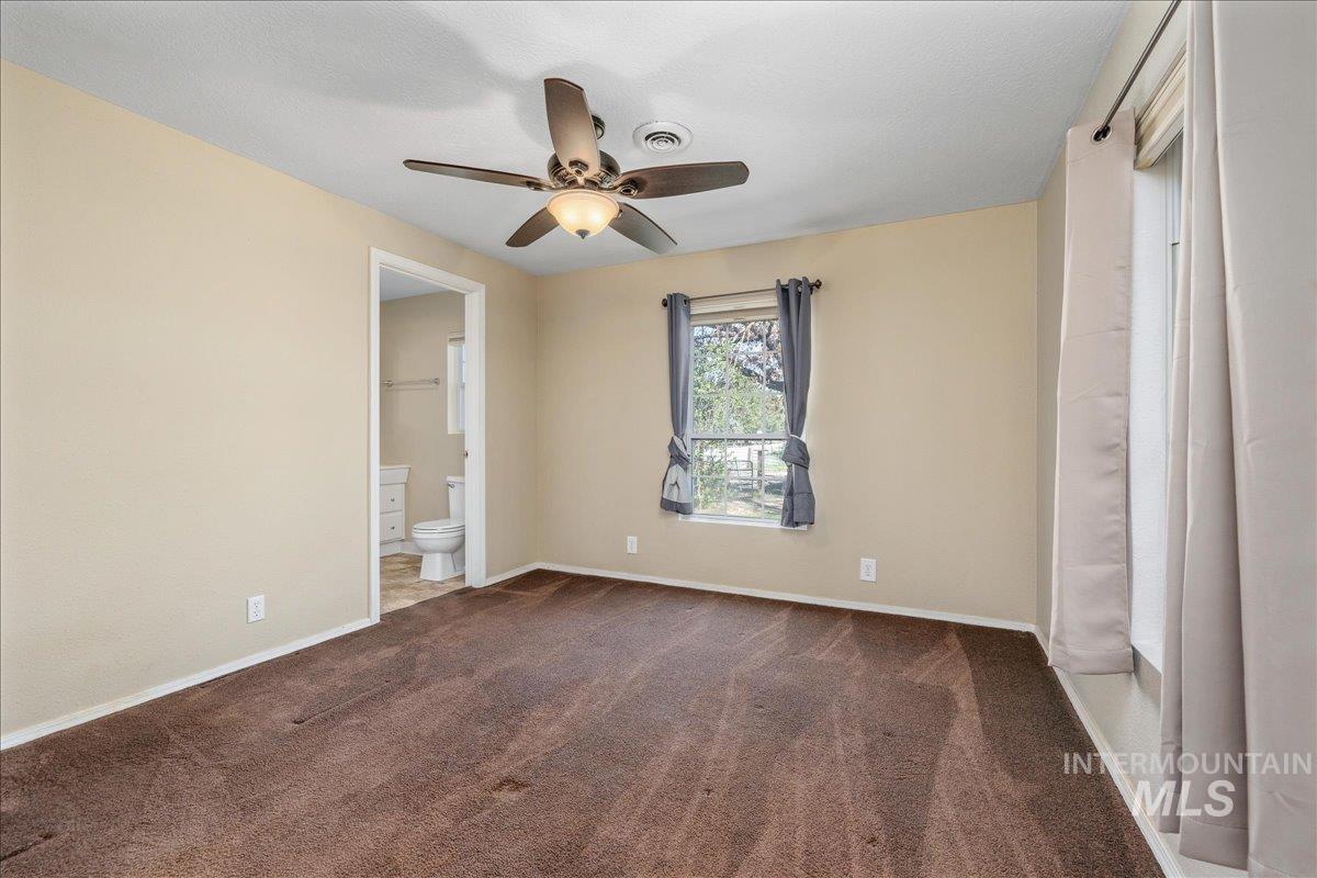 3002 Frozen Dog Road Emmett, ID 83617 - Photo 27 of 50 Unfurnished bedroom with a ceiling fan, ensuite bath, and dark carpet