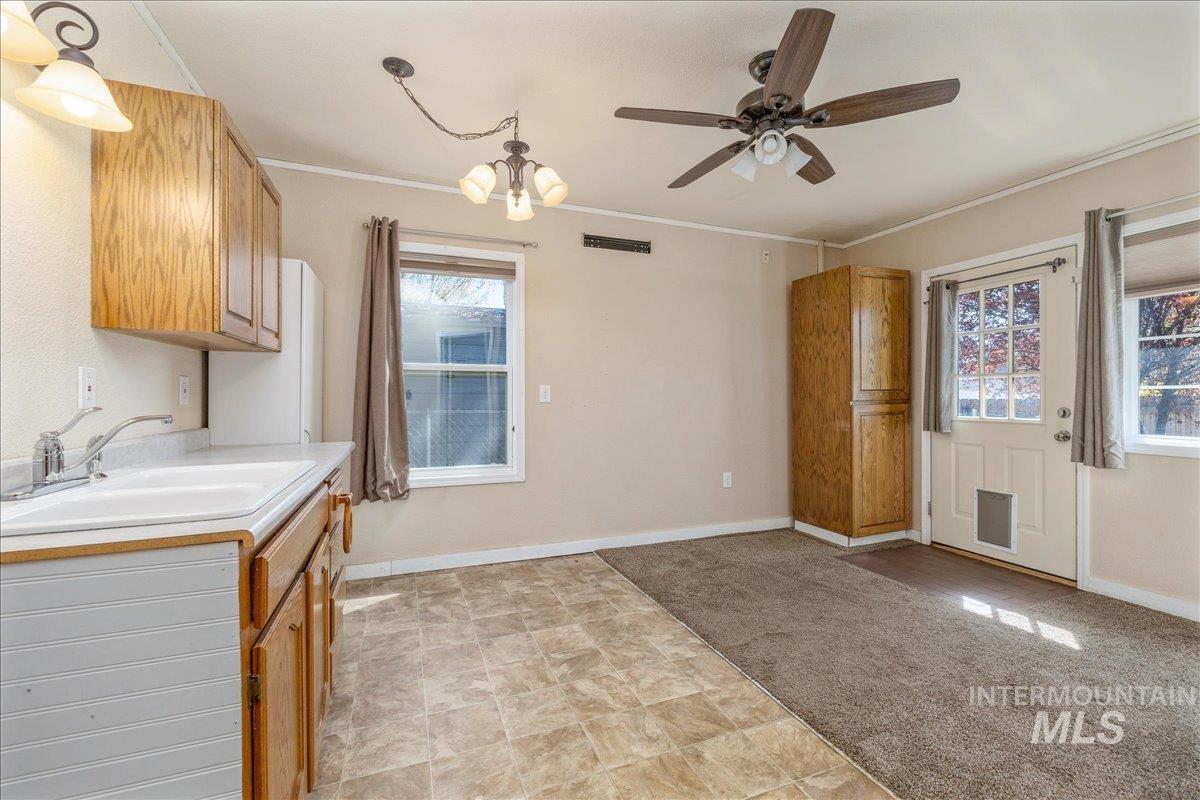 3002 Frozen Dog Road Emmett, ID 83617 - Photo 30 of 50 Kitchen with light countertops, light colored carpet, ceiling fan, ornamental molding, and hanging lights