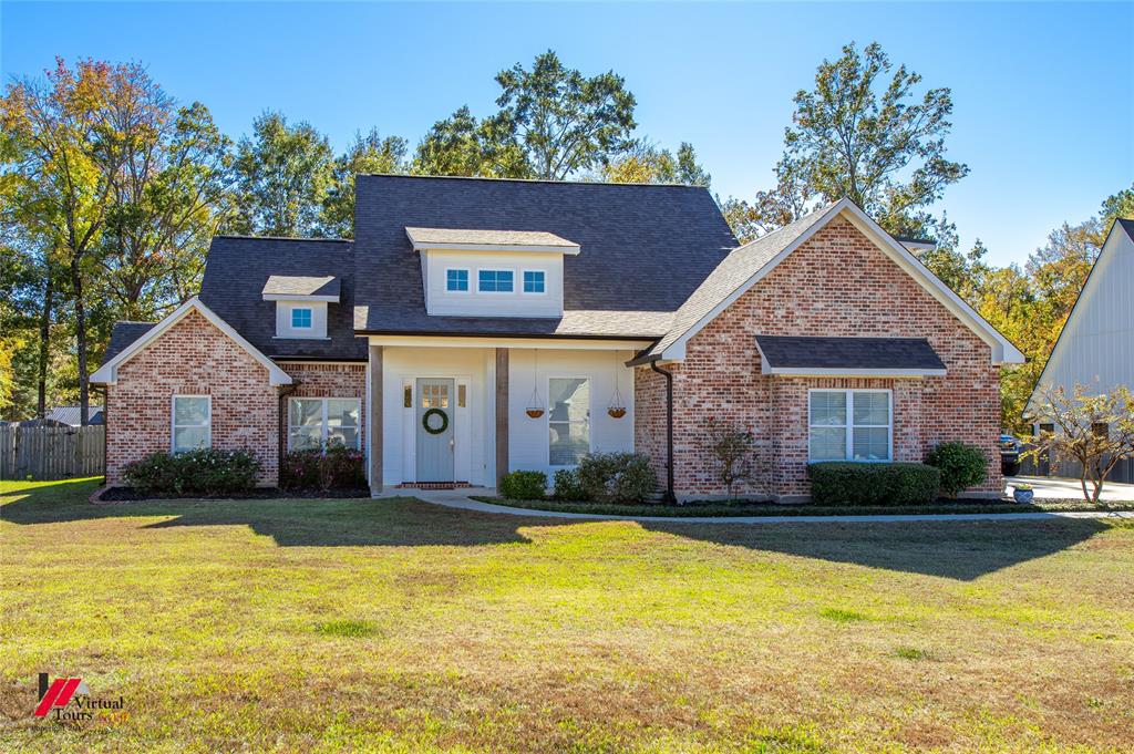 a front view of house with yard and trees in the background