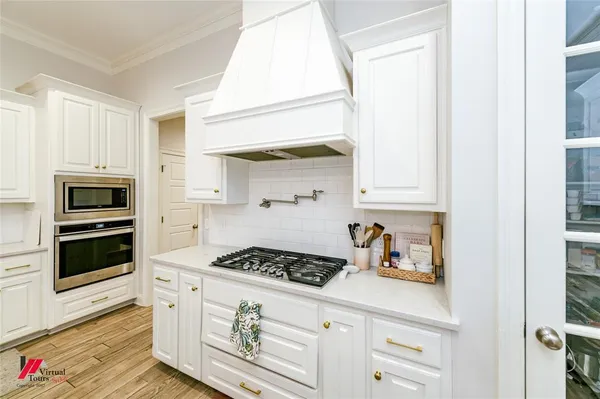 a kitchen with stainless steel appliances a stove and white cabinets