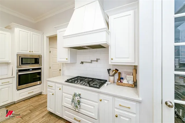 a kitchen with stainless steel appliances a stove and white cabinets