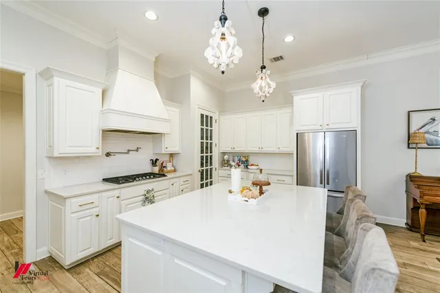 a kitchen that has a lot of white cabinets and stainless steel appliances