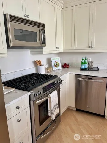a kitchen with stainless steel appliances white cabinets and a stove top oven