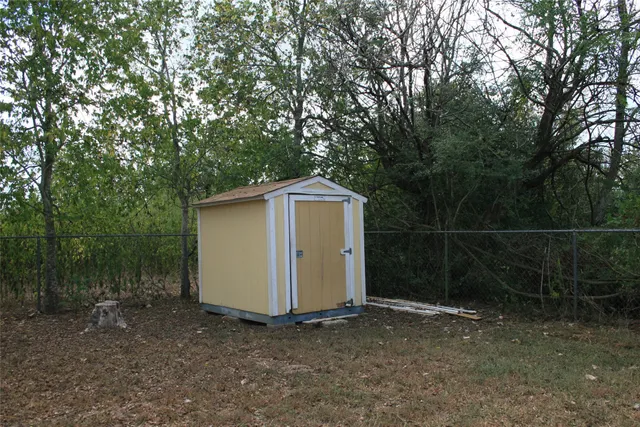 a backyard of a house with lots of plants and large tree