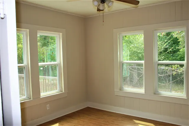 a view of an empty room with wooden floor and a window