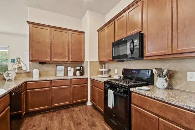 a kitchen with stainless steel appliances granite countertop a stove a sink and a microwave