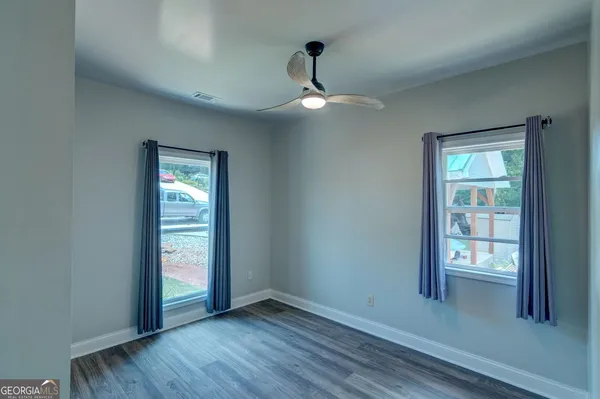 an empty room with wooden floor chandelier and windows