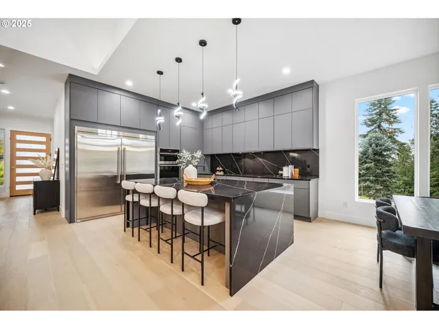 a kitchen with stainless steel appliances kitchen island granite countertop a table chairs and a living room