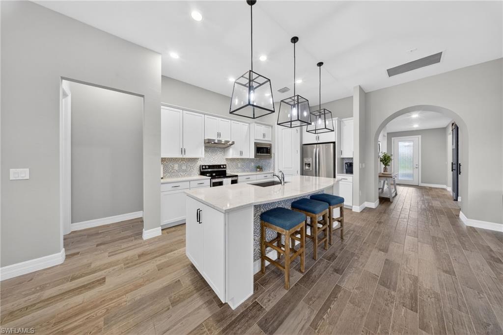 11920 Bourke Place Fort Myers, FL 33913 - Photo 8 of 45 a kitchen with stainless steel appliances kitchen island a wooden floor and white cabinets