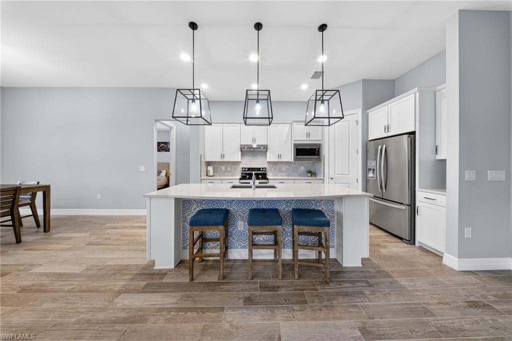 11920 Bourke Place Fort Myers, FL 33913 - Photo 9 of 45 a open kitchen with stainless steel appliances granite countertop a dining table chairs sink refrigerator and microwave