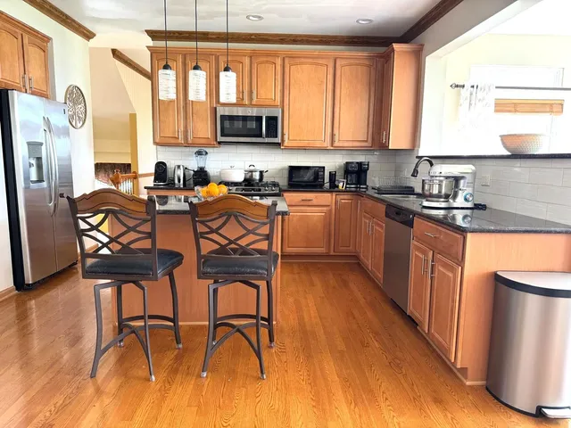 a kitchen with stainless steel appliances granite countertop wooden floors a stove top oven a sink a dining table and chairs