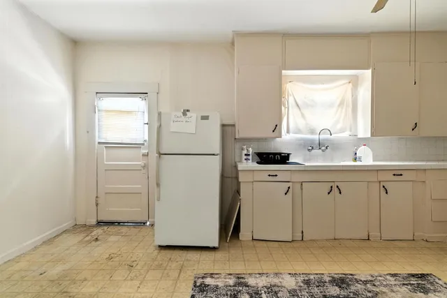 a kitchen with white cabinets and refrigerator