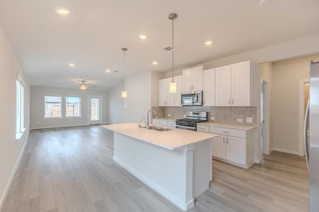 a kitchen with kitchen island a sink a stove a refrigerator and white cabinets