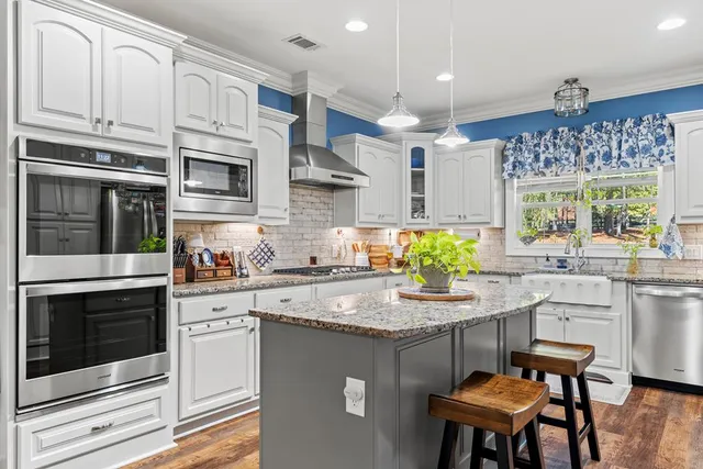 a kitchen with stainless steel appliances granite countertop a stove a sink and a microwave