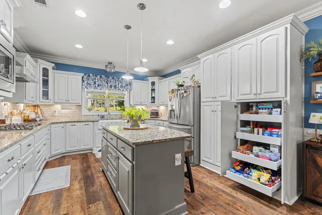 a kitchen with stainless steel appliances granite countertop a refrigerator a stove and a wooden floors