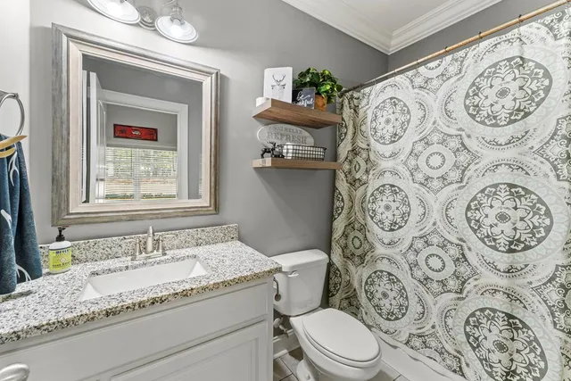 a bathroom with a granite countertop toilet a sink and a mirror