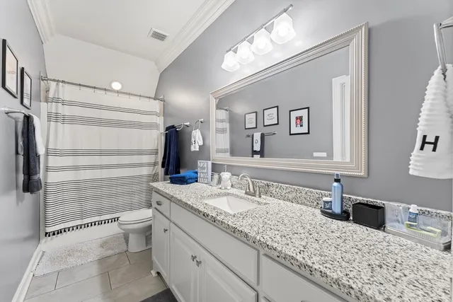 a bathroom with a granite countertop sink a toilet and mirror