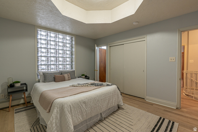 33 North 200 East Logan, UT 84321 - Photo 24 of 54 Bedroom featuring a textured ceiling, a closet, light wood-style floors, and a baseboard heating unit