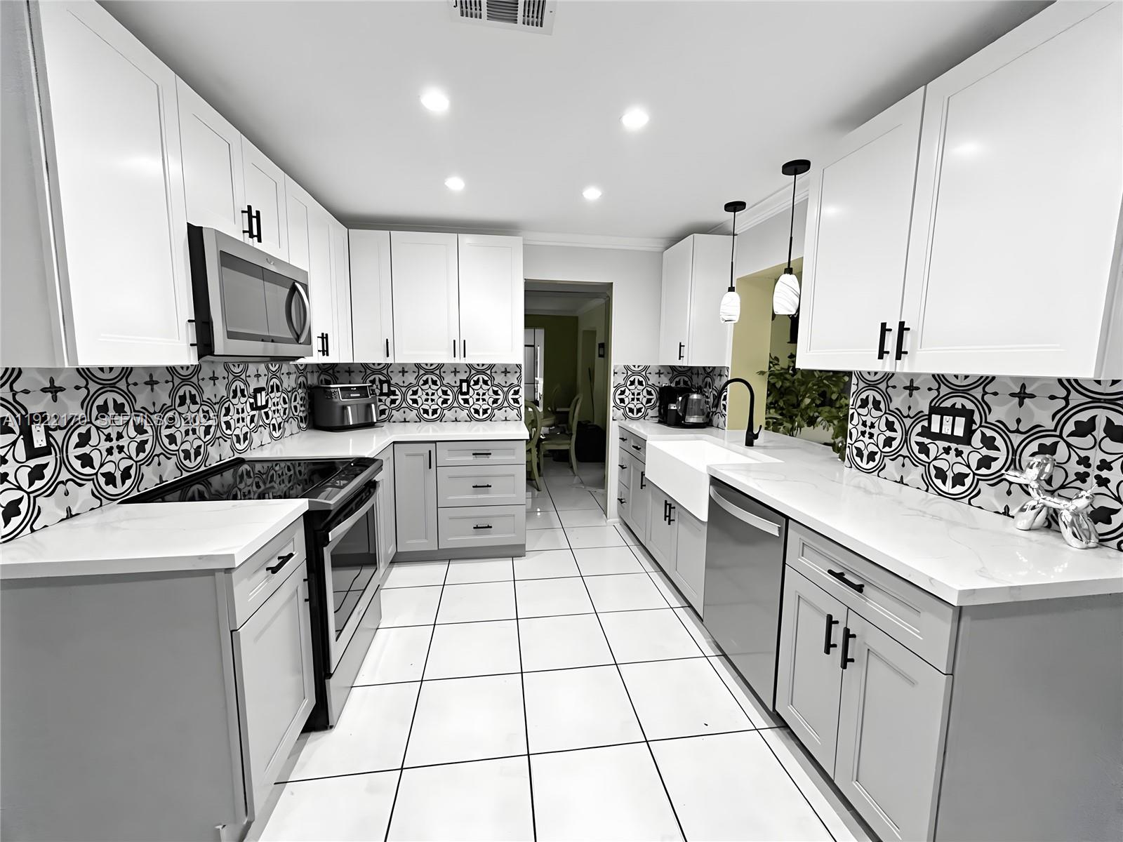 4905 Northwest 49th Road Tamarac, FL 33319 - Photo 4 of 25 a kitchen with stainless steel appliances a sink stove top oven and cabinets