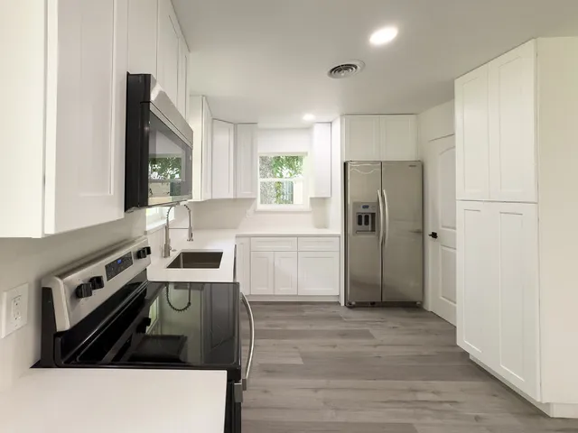 a kitchen with granite countertop a refrigerator stove and sink