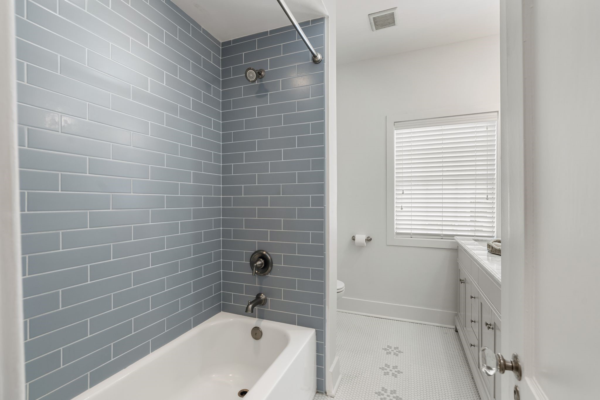 714 Ridge Street Houston, TX 77009 - Photo 17 of 36 In the beautifully renovated windowed bathroom, lovely tilework runs from the penny tile floors to the elongated subway tile in the large tub/shower.