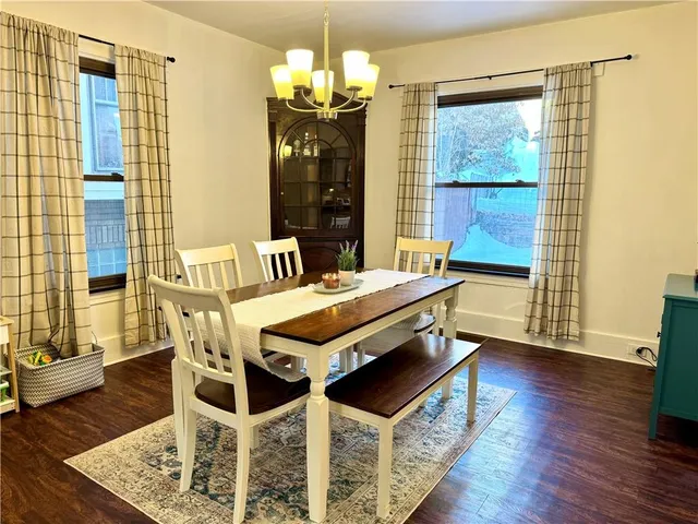 a dining room with wooden floor a chandelier a wooden table and chairs