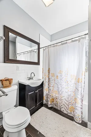a bathroom with a sink a toilet a mirror and shower curtain