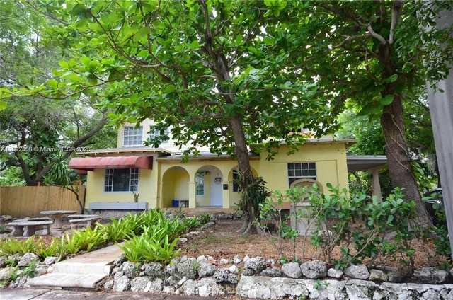 a view of a white house with large windows and a large tree