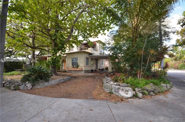 a view of a house with a yard and large tree