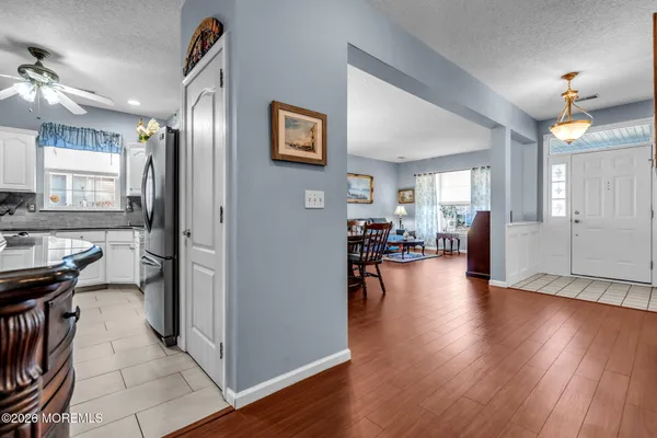 a kitchen with stainless steel appliances granite countertop a refrigerator a stove a microwave oven a sink dishwasher and white cabinets with wooden floor