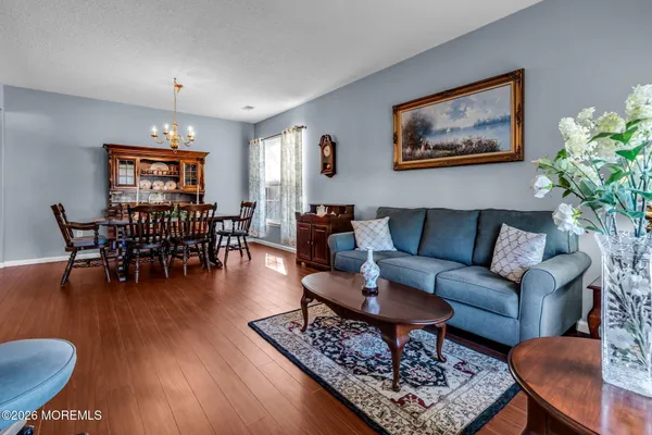 a dining room with wooden floor a chandelier a wooden table and chairs