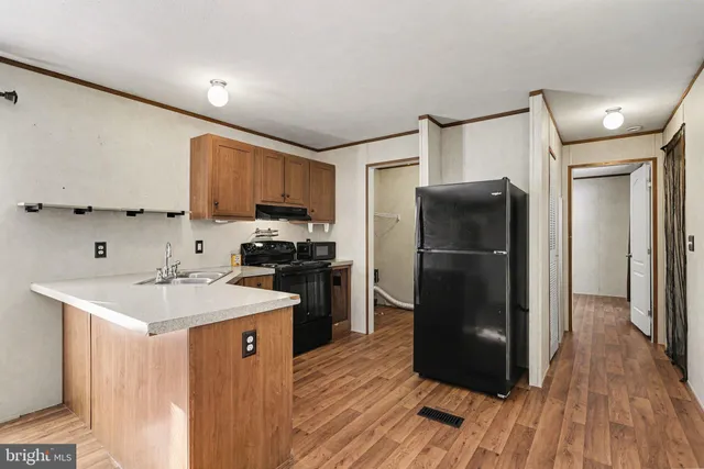 a kitchen with a refrigerator a sink and wooden floor