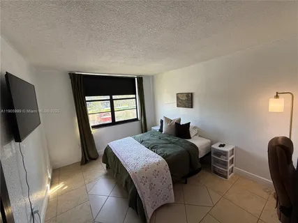 a bedroom with a bed a flat screen tv and window