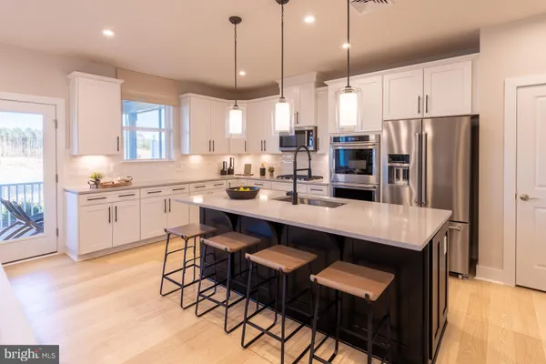 a kitchen with stainless steel appliances granite countertop a table chairs sink refrigerator and cabinets