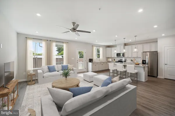 a living room with furniture kitchen view and a large window