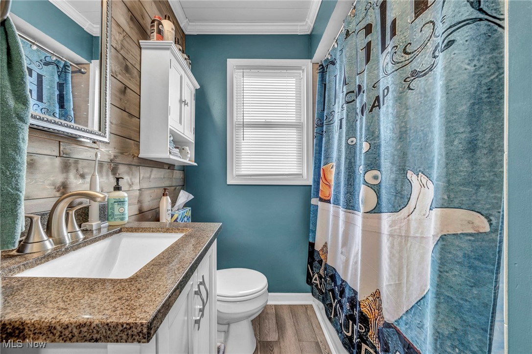 3285 Stoney Ridge Road Avon, OH 44011 - Photo 23 of 43 Full bathroom featuring curtained shower, ornamental molding, light wood-type flooring, vanity, and wood walls