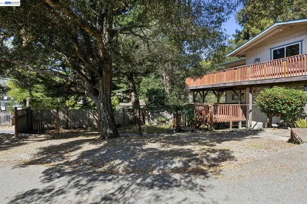 a view of a house with large tree and wooden fence