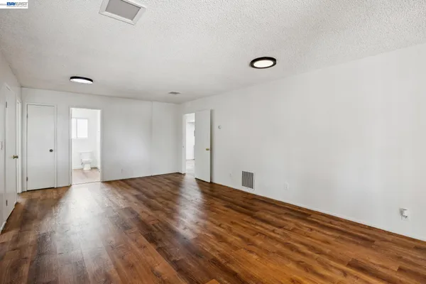 an empty room with wooden floor and windows