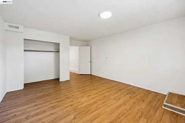 a view of an empty room with wooden floor and closet