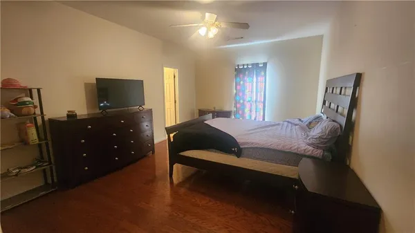 a bedroom with a bed and a flat tv screen on dresser