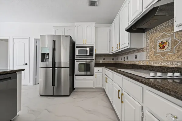a kitchen with stainless steel appliances granite countertop a refrigerator a stove and a sink