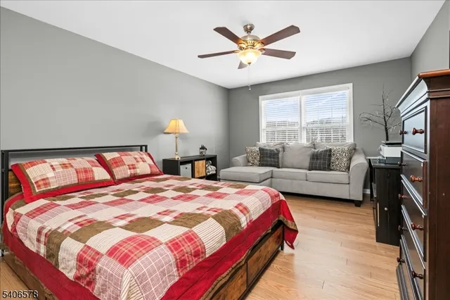 a bedroom with a bed a couch and a flat tv screen on dresser