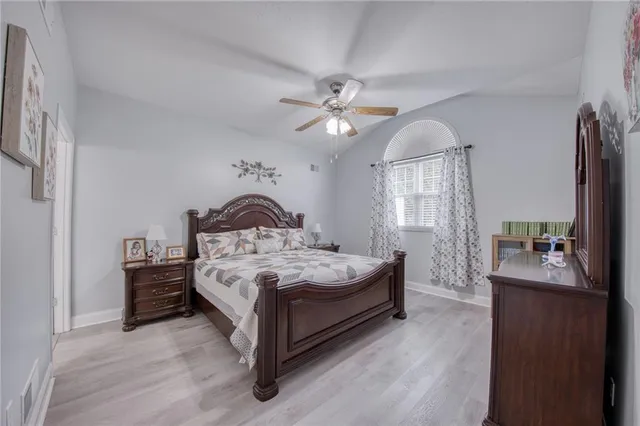 a spacious bedroom with a bed a chandelier and a dresser