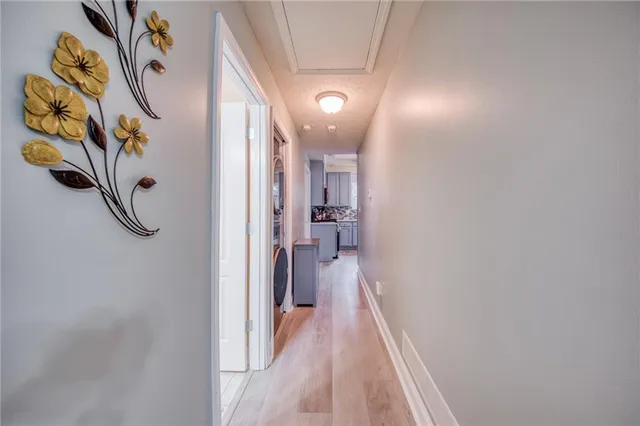 a view of a hallway with wooden floor and a bathroom
