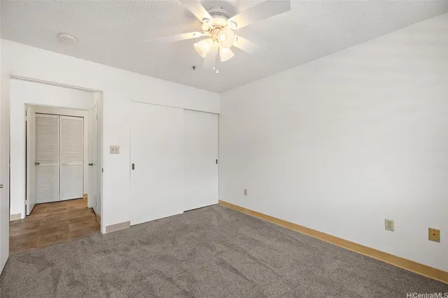 an empty room with a chandelier fan and closet area