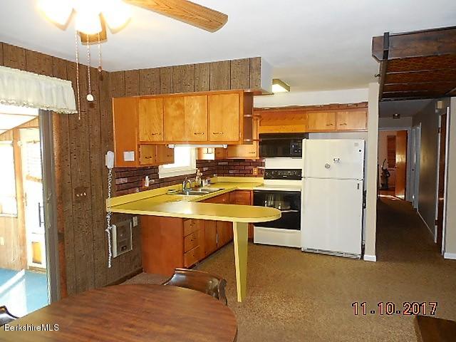 184 Washington Mountain Road Lee, MA 01238 - Photo 7 of 26 a kitchen with stainless steel appliances a stove a refrigerator a sink and white cabinets with wooden floor