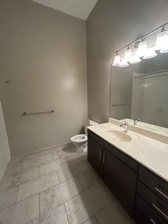 a bathroom with a granite countertop sink a toilet and a mirror